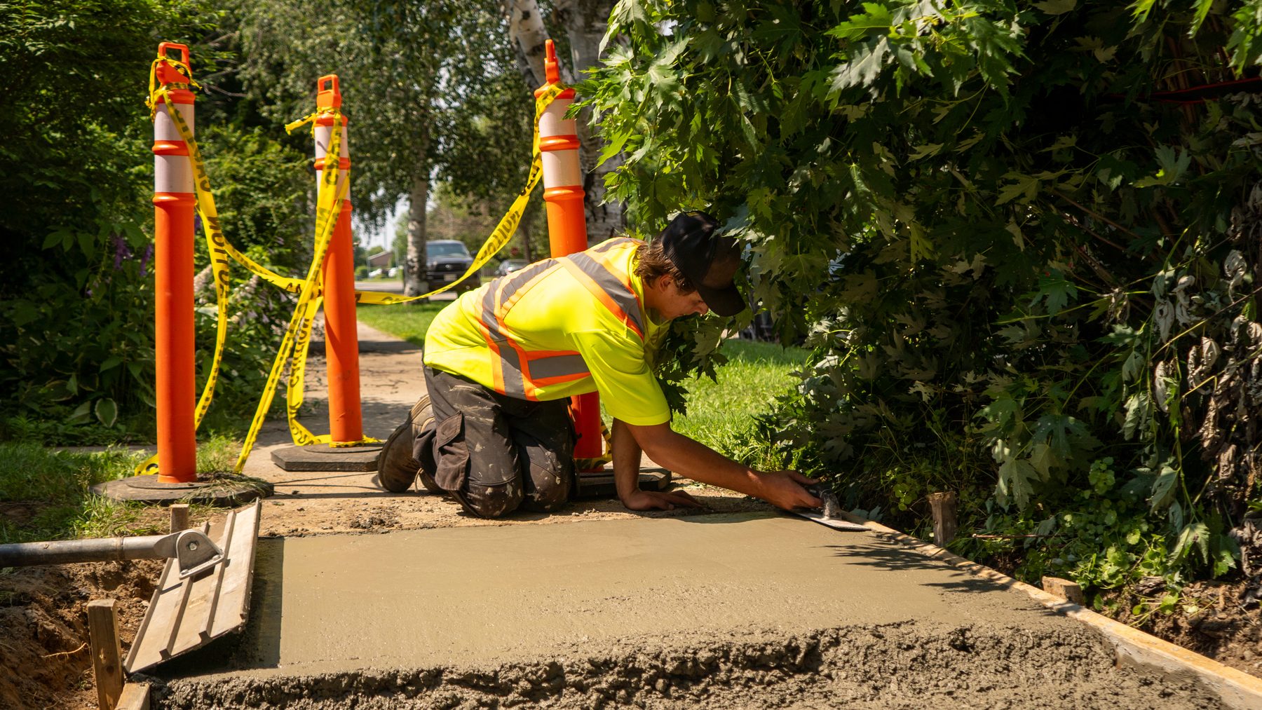 Crew finishing concrete work behind orange safety barriers