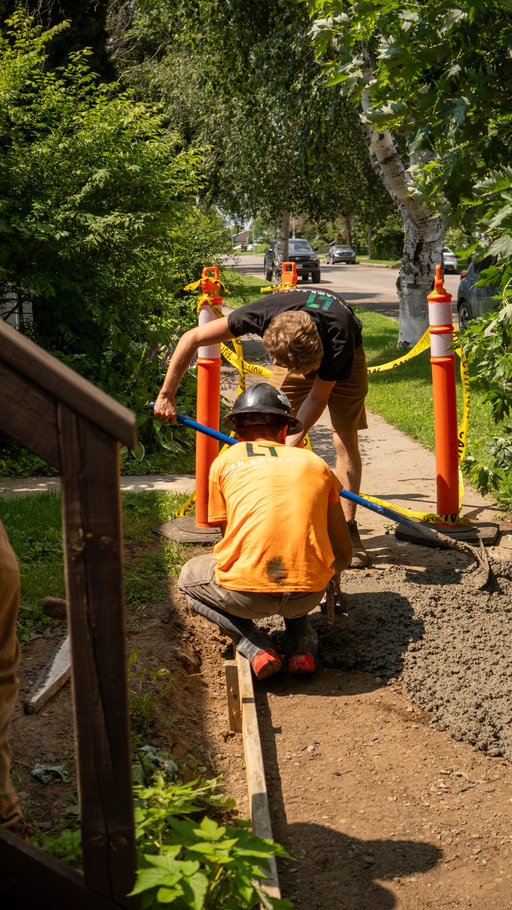 Landscaping crew installing a walkway on a residential property in summer